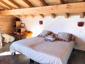 A bedroom with a wooden ceiling, a bed with a white bedspread, a teddy bear, a shelf with folded clothes, and a polar bear statue. - Chalet with superb view of the estate (Vars)