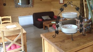 Un interior de cabaña acogedor con una mesa de comedor de madera, un sofá y un espejo en la pared.