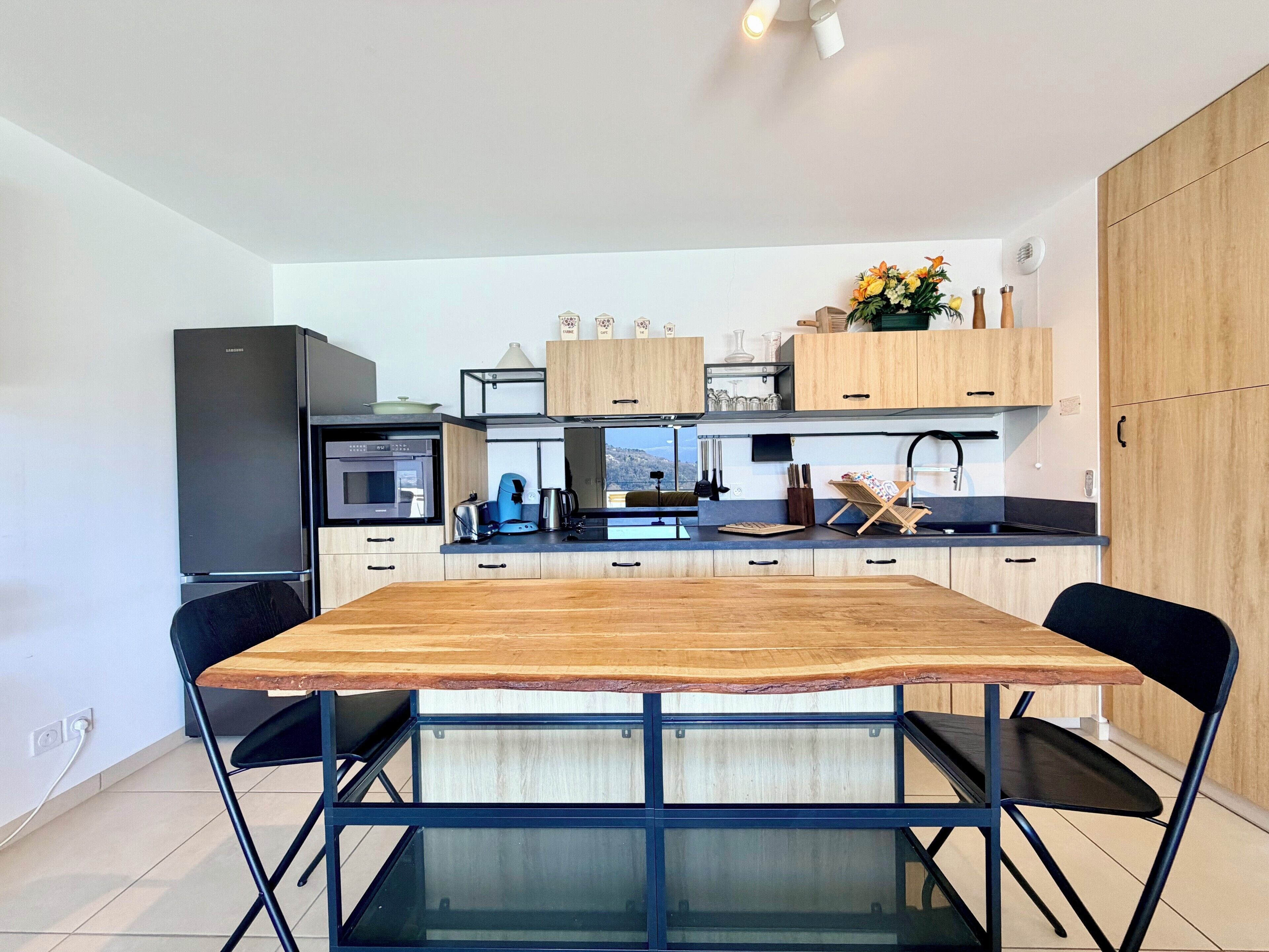 Eine moderne Küche mit einem Holzespeisetisch, schwarzen Stühlen und einem eingebauten Backofen.