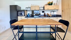 A modern kitchen with a wooden dining table, black chairs, and a built-in oven. - Comfortable T3 with terrace and garage! (Aix-les-Bains)