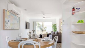 A dining area with a round wooden table, white chairs, and a view to the outside.