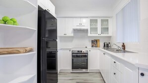 A kitchen with white cabinets, a black refrigerator, an oven, and a sink.