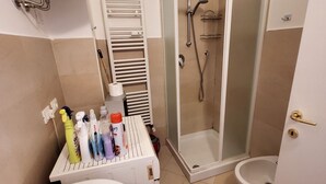 Un bagno con doccia, WC e un piccolo tavolo con articoli da toilette.