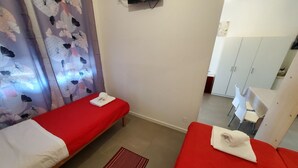 Una camera con due letti singoli, una scrivania e un armadio.