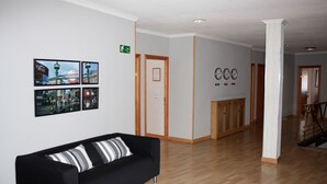 Un salon moderne avec un canapé noir, un plancher en bois et une colonne en marbre.
