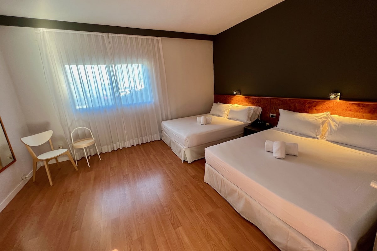 Ein Hotelzimmer mit zwei Betten, einem kleinen Tisch und einem Stuhl.