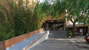 Un bâtiment à la façade en briques, doté d’une entr ée couverte et d’un espace de stationnement où se trouve une voiture.