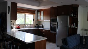 A modern kitchen with wooden cabinets, a stainless steel refrigerator, and a large island. - Immaculate 3-bed House in Pentakomo (Pentakomo)
