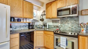 A modern kitchen with wooden cabinets, stainless steel appliances, and a tiled backsplash.