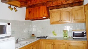 Une cuisine avec des meubles de rangement en bois, une cuisinière à gaz, un four à micro-ondes et un grille-pain.
