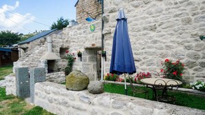 Un bâtiment en pierre avec un mur en pierre, un parasol bleu et une table avec des chaises.