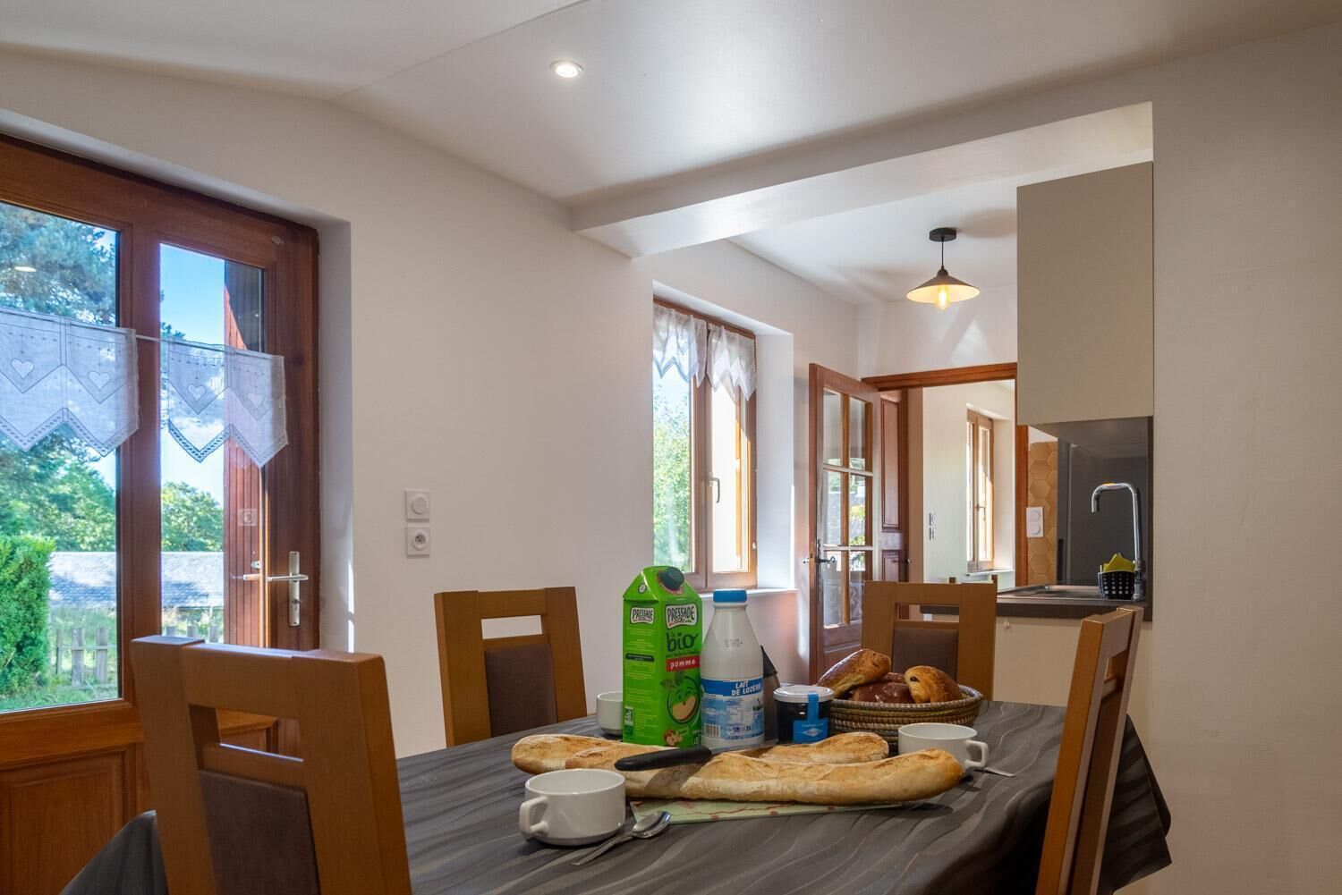 Comedor con una mesa preparada para dos personas, incluyendo pan, una botella de leche y una taza.