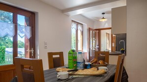 A dining area with a table set for two, including bread, a bottle of milk, and a cup. - La Maison Rocher - Fournels (FOURNELS)