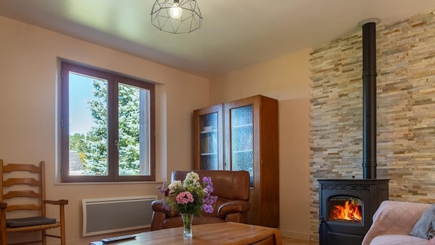 A cozy living room with a fireplace, a wooden coffee table, a cushioned chair, and a sofa. - La Maison Rocher - Fournels (FOURNELS)