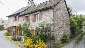 A stone house with a sloped roof, wooden shutters, and a small garden with flowering plants. - 3/4 pers rental in Grandviala (LA CHAZE-DE-PEYRE)