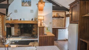 Una cocina rústica con chimenea, armarios de madera y un comedor con una mesa dispuesta para dos personas.