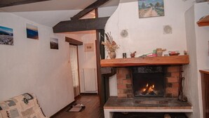 Una sala de estar acogedora con chimenea, vigas de madera y un sofá estampado.