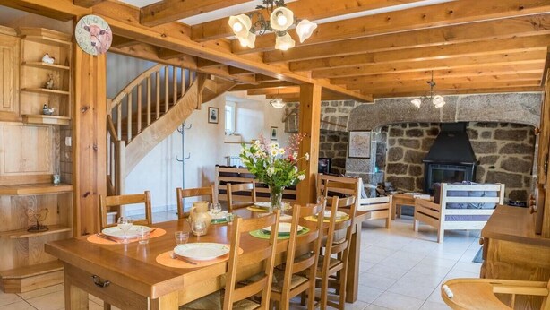 A wooden dining area with a staircase, stone fireplace, and wooden shelves.