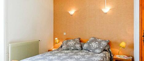 Une chambre à coucher avec un lit, deux lampes de chevet, une table de chevet et un radiateur.