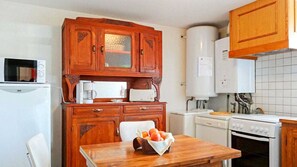 Cozinha compacta com armários de madeira, micro-ondas, torradeira, pia e fogão.