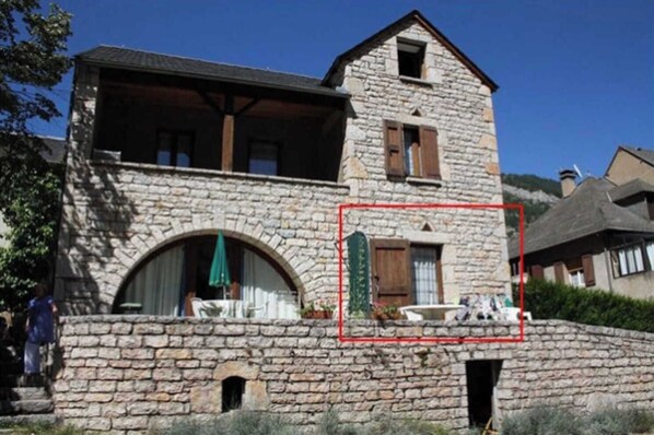 Un edificio de piedra con un balcón, una ventana pequeña y una puerta.