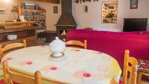 Ein gemütliches Wohnzimmer mit Kamin, Holzmöbeln und einem Esstisch mit Blumenmuster.