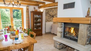 A cozy dining area with a fireplace, wooden furniture, and a bookshelf.