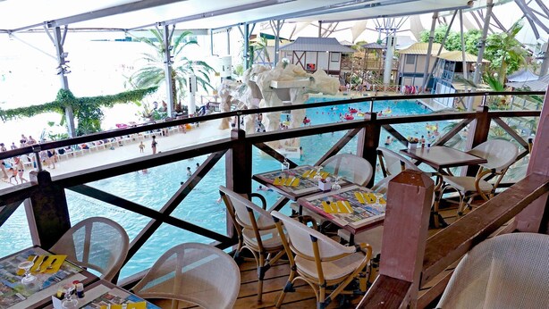 A poolside restaurant with outdoor seating overlooking a pool area, featuring tables with menus and glasses. - 2 Bedroom Apartment in Blaye (Blaye)