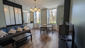 A modern living room with a sofa, a dining table, and a TV. - 2 Bedroom Apartment in Blaye (Blaye)