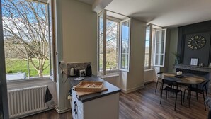 A kitchen with large windows, a wooden countertop, and a dining area with chairs and a table. - 2 Bedroom Apartment in Blaye (Blaye)
