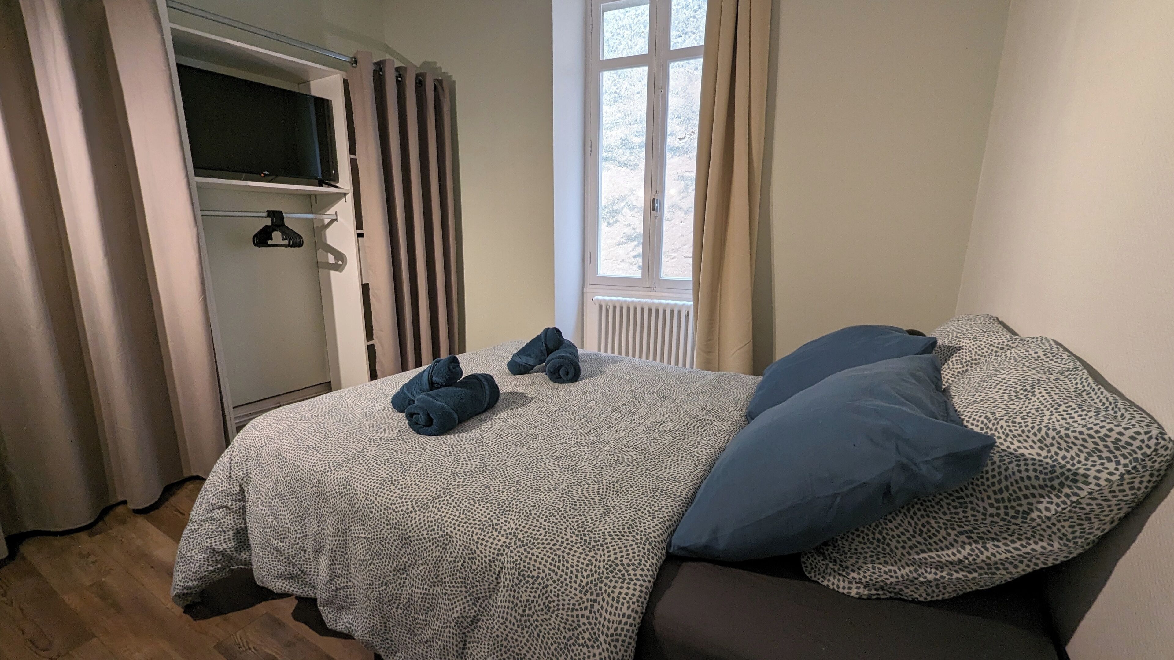 Une chambre à coucher avec un lit, une armoire, une fenêtre et un radiateur.