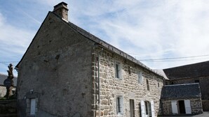 A stone building with a steep roof, multiple windows, and a small porch area. - Gîtes de France à Veyrès - SAINT-LAURENT-DE-VEYRES (ST LAURENT DE VEYRES)