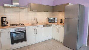 A modern kitchen with white cabinets, stainless steel appliances, and a light wood countertop. - Gîtes de France à Veyrès - SAINT-LAURENT-DE-VEYRES (ST LAURENT DE VEYRES)