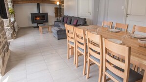 A cozy living area with a stone fireplace, a sofa, and a dining table set for six. - Gîtes de France à Veyrès - SAINT-LAURENT-DE-VEYRES (ST LAURENT DE VEYRES)
