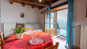 A dining area with a red tablecloth, wooden chairs, a wicker basket, and a view through a glass door. - House (POMPIDOU (LE))