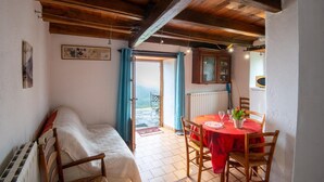 A cozy room with a bed, a dining table with chairs, a wooden ceiling, and a view through an open door. - House (POMPIDOU (LE))