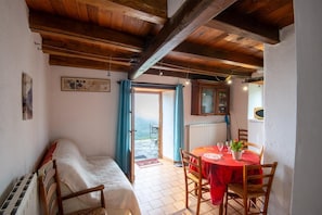 Una habitación con cama, una mesa de comedor con sillas, un armario y vistas a través de una puerta abierta.
