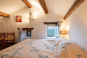 A bedroom with a bed, a window, a lamp, and a chair.