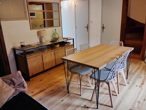 Un comedor con mesa y sillas de madera, una cocina con armarios y un microondas, y un espejo sobre la encimera.