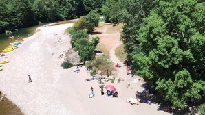 Ein Flussufer mit Sandstrand, Bäumen und felsigen Klippen.