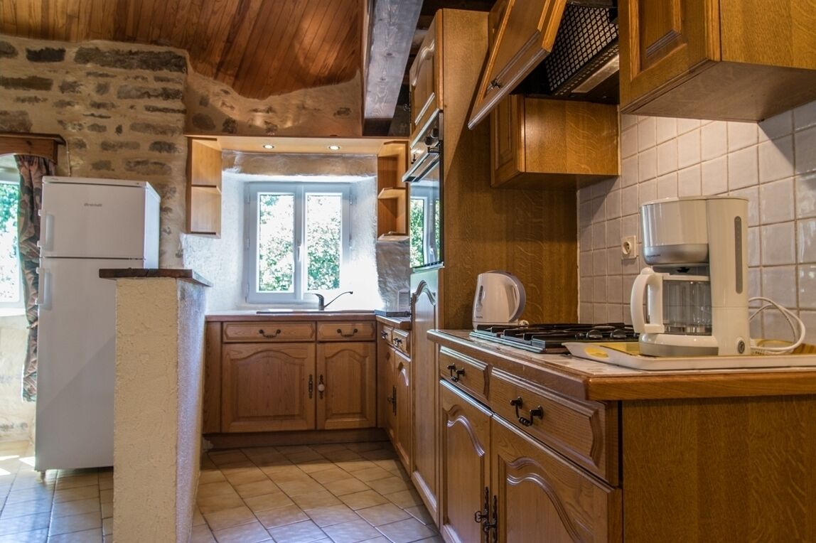 A rustic kitchen with wooden cabinets, a white refrigerator, and a coffee maker.