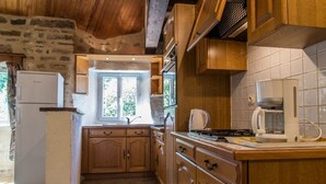 Una cocina rústica con armarios de madera, un refrigerador blanco y una cafetera.