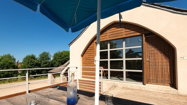 A wooden deck with a glass table, a bottle, and a glass.