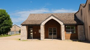 A small, stone building with a gabled roof and wooden doors, likely a guesthouse or lodge.