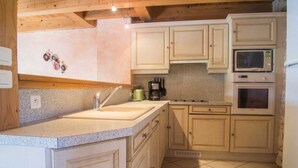 Une cuisine avec des meubles de couleur claire, un évier et un four à micro-ondes.