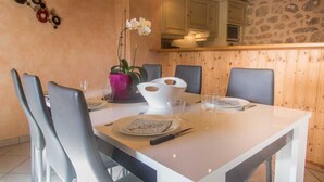 Un coin repas avec une table blanche, des chaises grises et une orchidée en pot.
