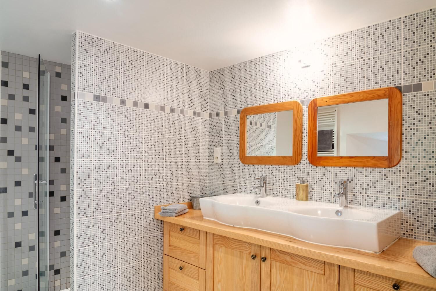 A bathroom with a large sink, two mirrors, and a shower.