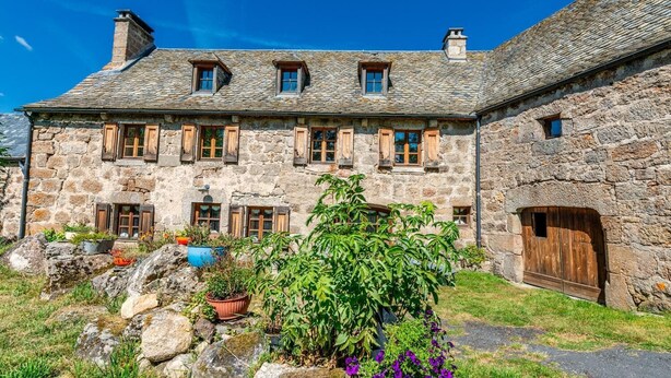 Un bâtiment en pierre doté de nombreuses fenêtres et d’une grande porte en bois.