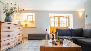 Un salon moderne avec une table basse en bois, un canapé, un meuble, une lampe et une fenêtre avec des rideaux.