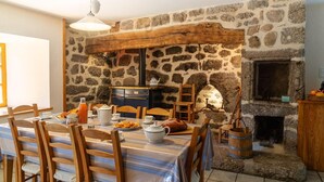 Un coin repas rustique avec un mur en pierre, des poutres en bois et une cheminée.